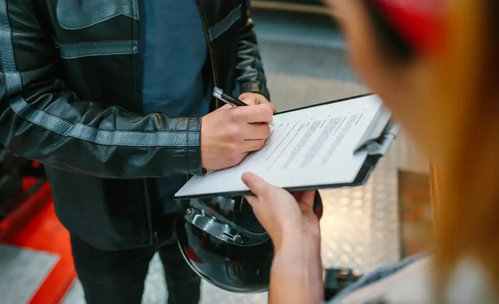 A motorcyclist signing paperwork.