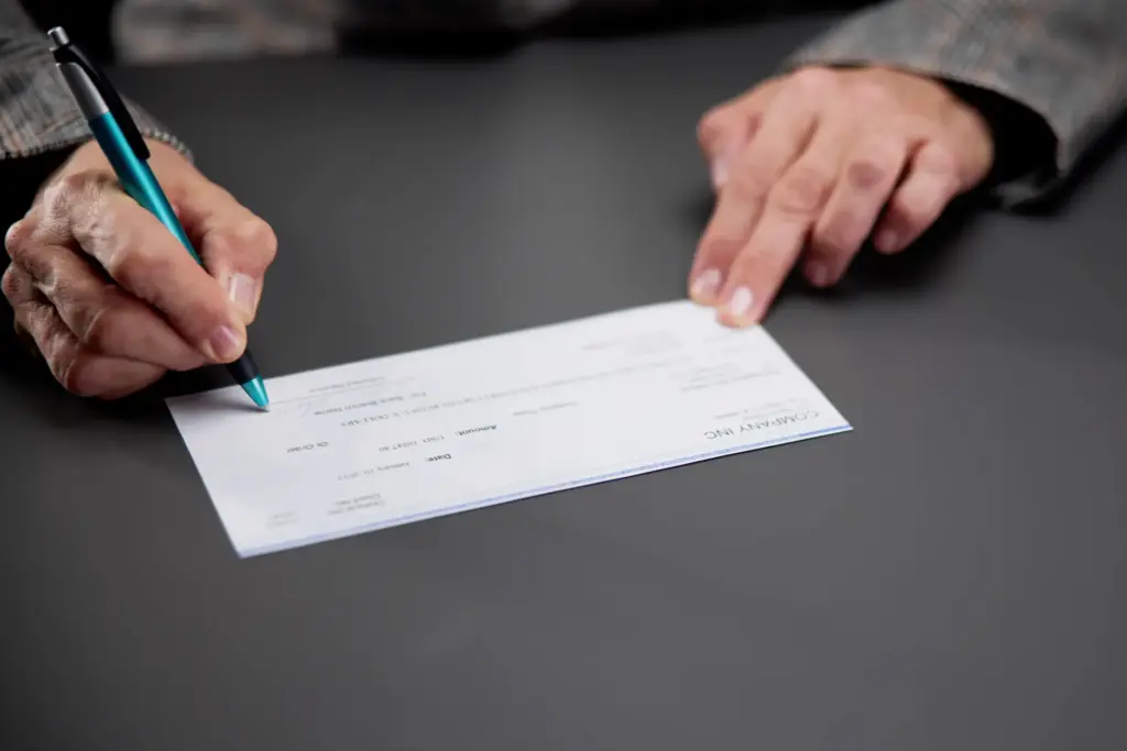 A person signing a check for an injury victim.