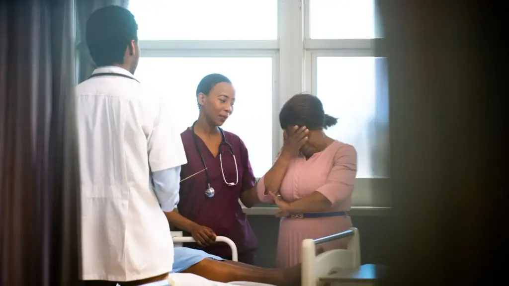 A crying woman in a hospital getting comforted by a nurse and doctor.