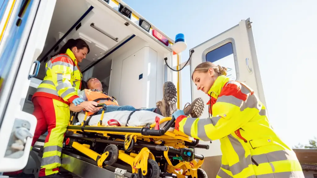 Two EMT operators carrying a man in an ambulance.