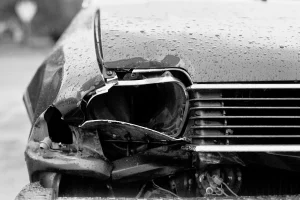 A car's broken headlight on a rainy day.