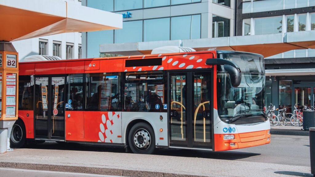 Bright red bus at one of its stops.