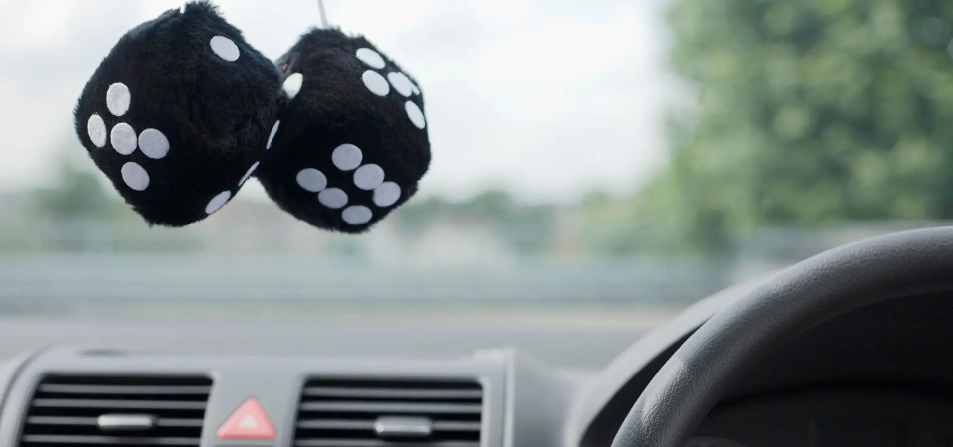 A pair of fuzzy dice hanging on a rearview mirror.