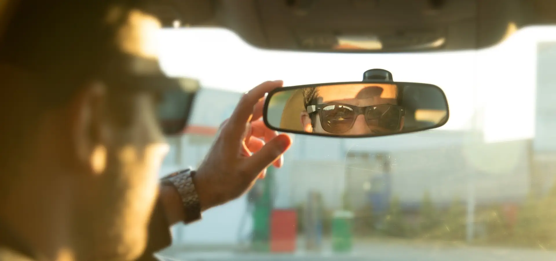 A man checking and adjusting his rearview mirror.