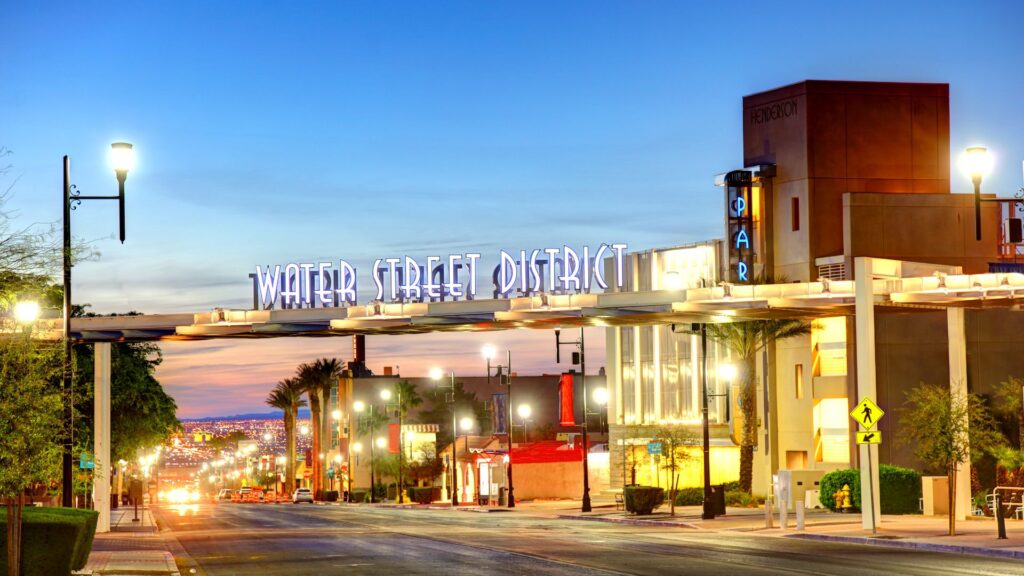 Brightly-lit nighttime view of Henderson City, Nevada with the "Water Street District" neon sign in view.