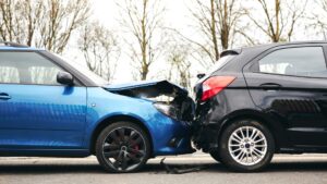Rear end car accident between a clue and black car.