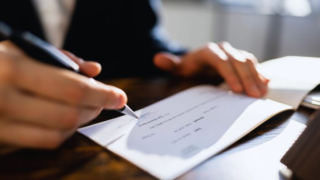 Personal injury attorney signing a check for a client.