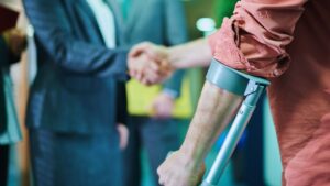Injured man in crutches shaking hands with a personal injury attorney.