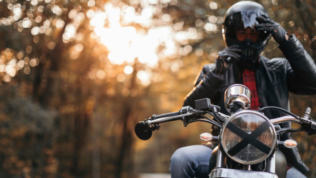 Man on motorcycle adjusting his helmet.