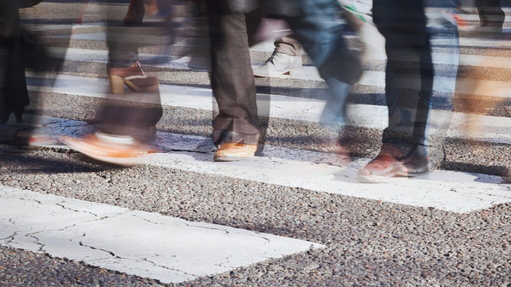 Low shot of pedestrians' feet as they cross at a crosswalk.