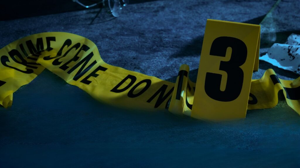 Yellow crime scene tape on a dark floor.