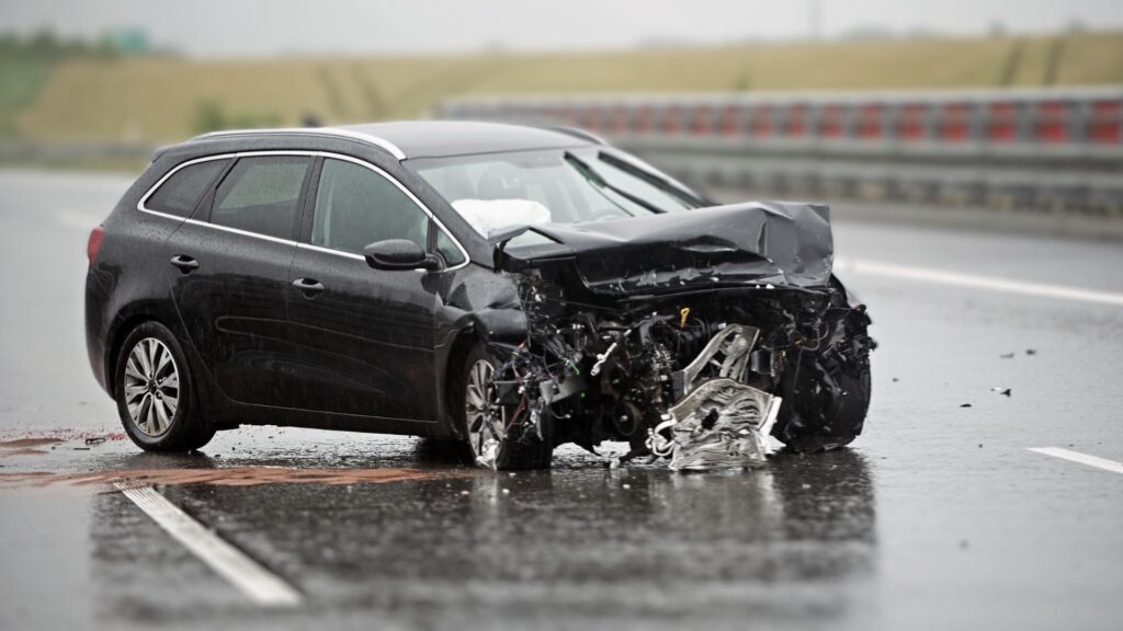 An SUV on a slippery wet road with severe bumper damage.