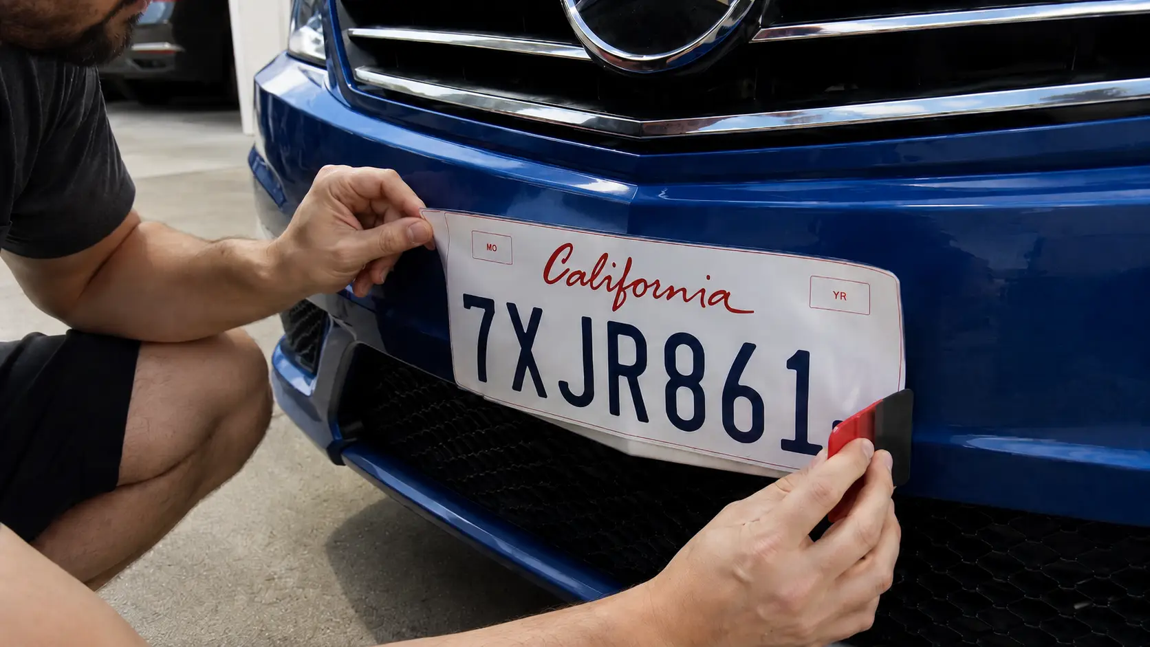 A man installing a license plate wrap on his car.