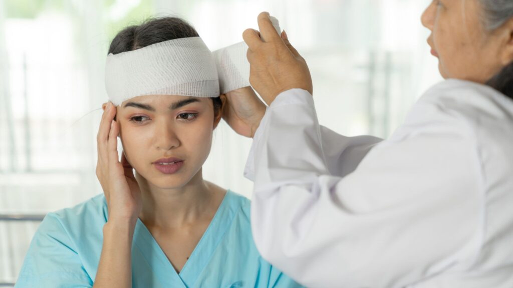 A doctor wrapping gauze around a woman's head.