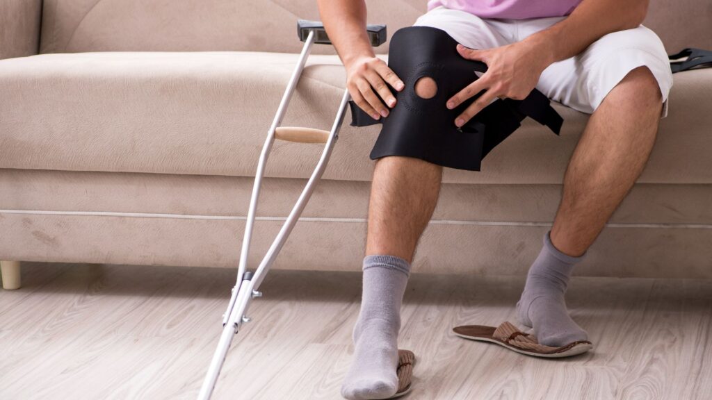 Hombre con lesión en la pierna sentado con muletas enseguida.