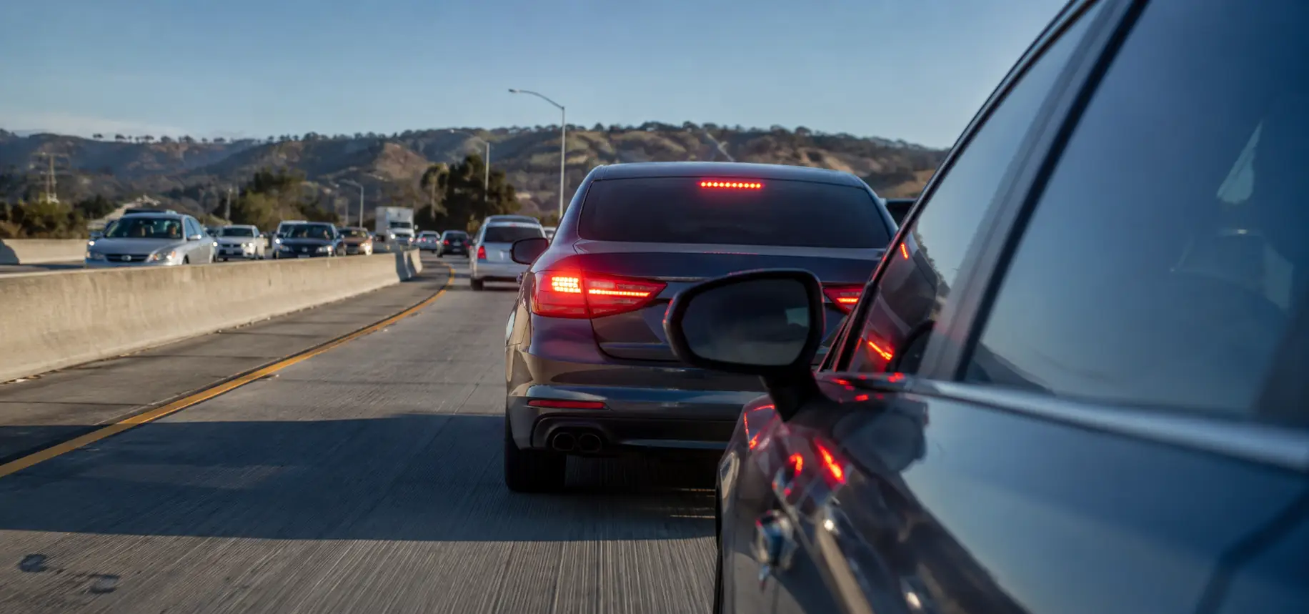 One car is braking hard in front of another car, with glowing red brake lights and a tense close following distance.