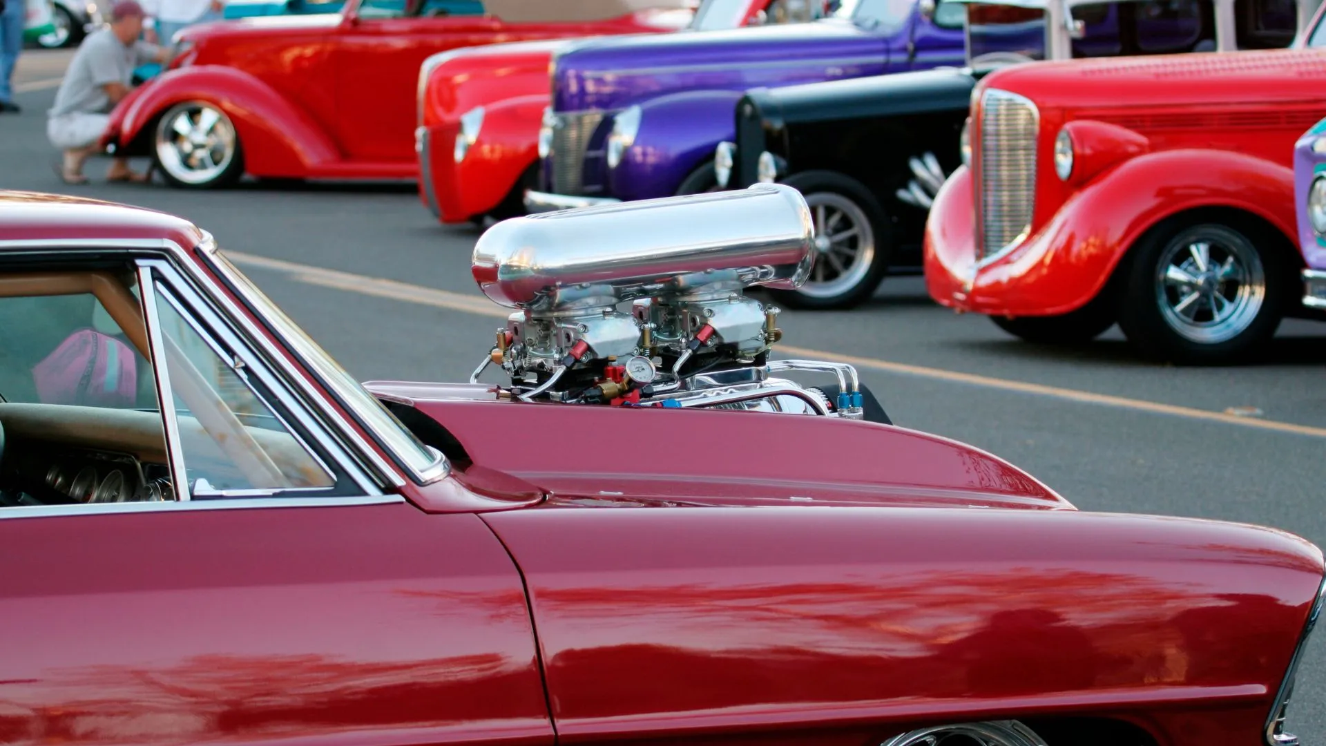A customized retro car with an engine popping out of its hood.