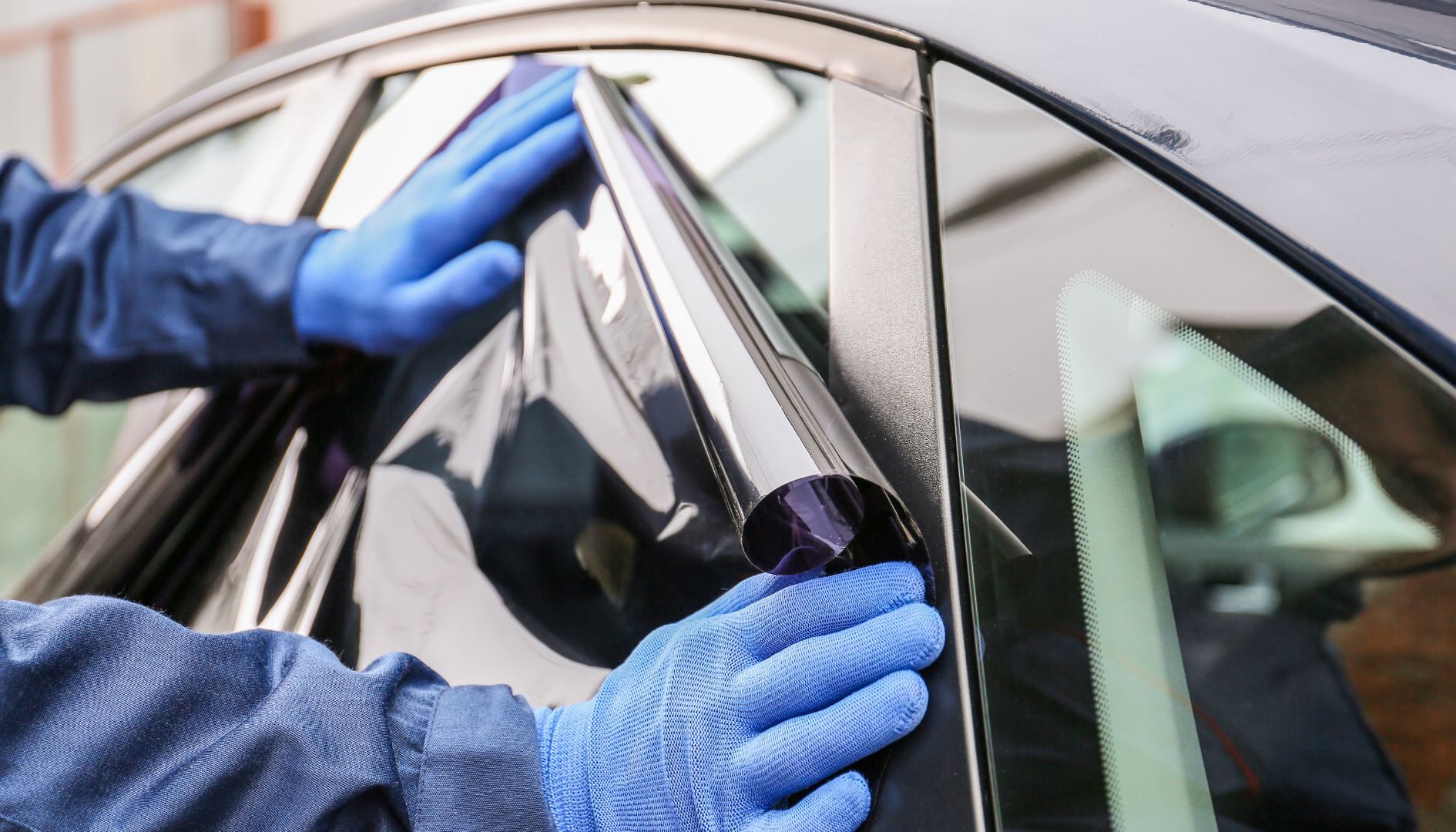Una persona colocando polarizado en las ventanas traseras de un automóvil.
