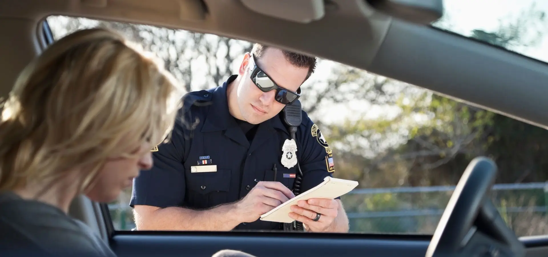 An officer writing a ticket to a driver.