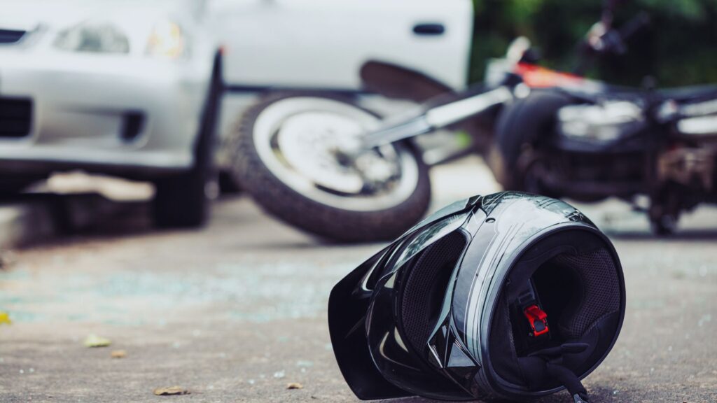 Un casco de moto tirado en frente de la escena de un accidente entre moto y carro.