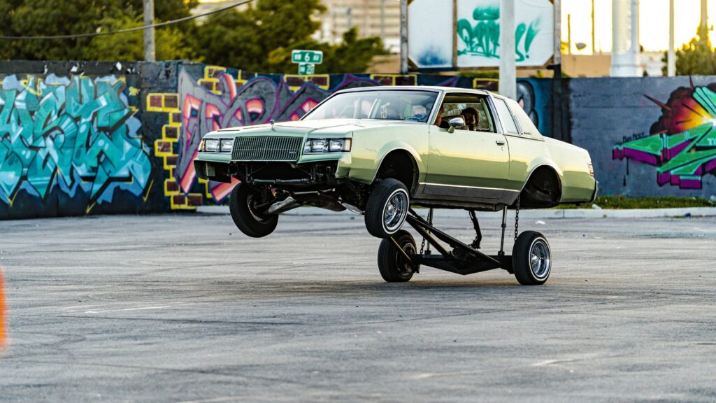 a green car jumping up with a hydraulics mod