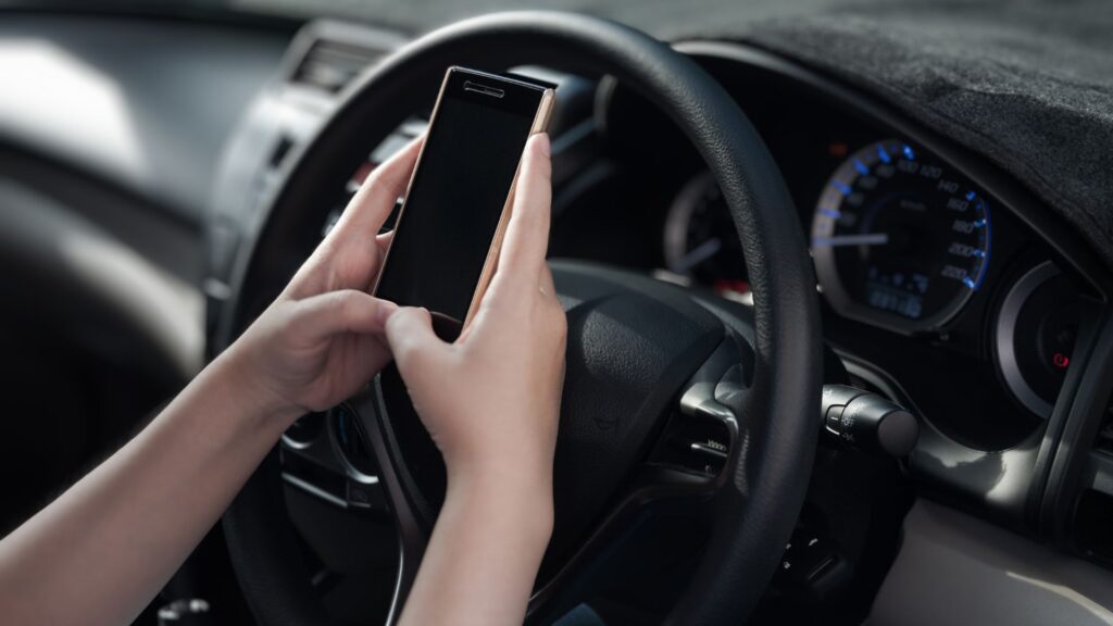 Una persona usando su teléfono celular mientras detrás del volante