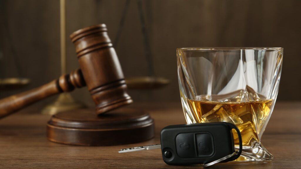 A gavel, a glass of whiskey, and a car key on a table.