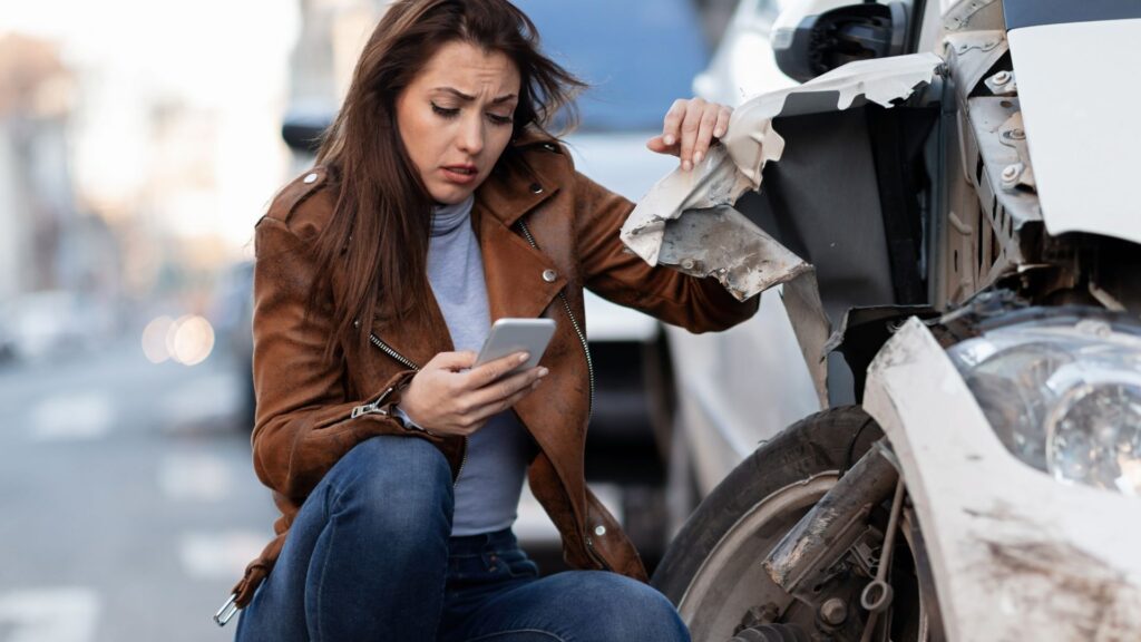 A woman getting on the phone after being involved in a car accident.