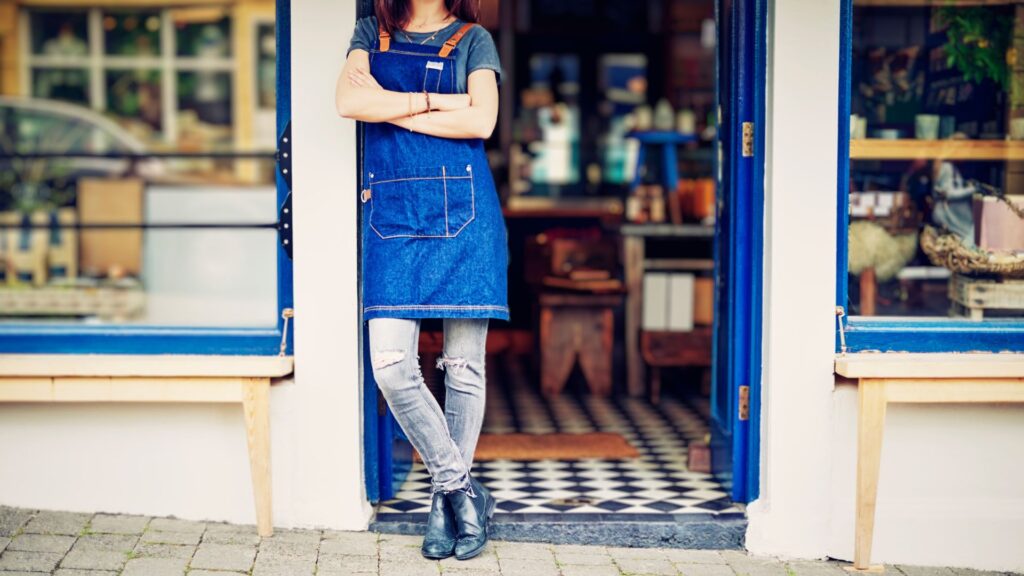 Una mujer parada en la entrada de su tienda.