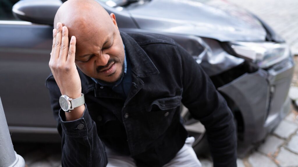 A man who is holding his head in discomfort after a car accident.