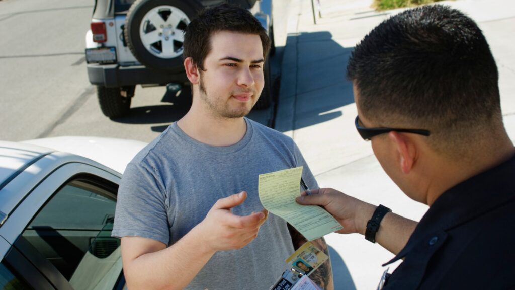 A man receiving a ticket from a police officer.