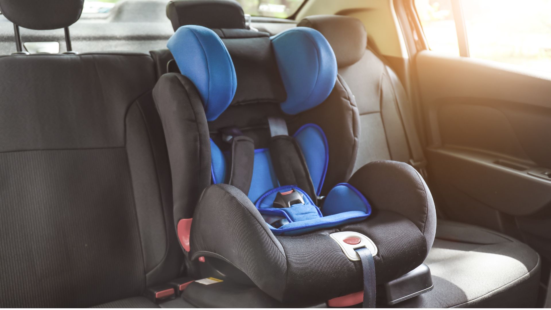 Una silla de auto azul y negra instalada en el asiento trasero de un carro.