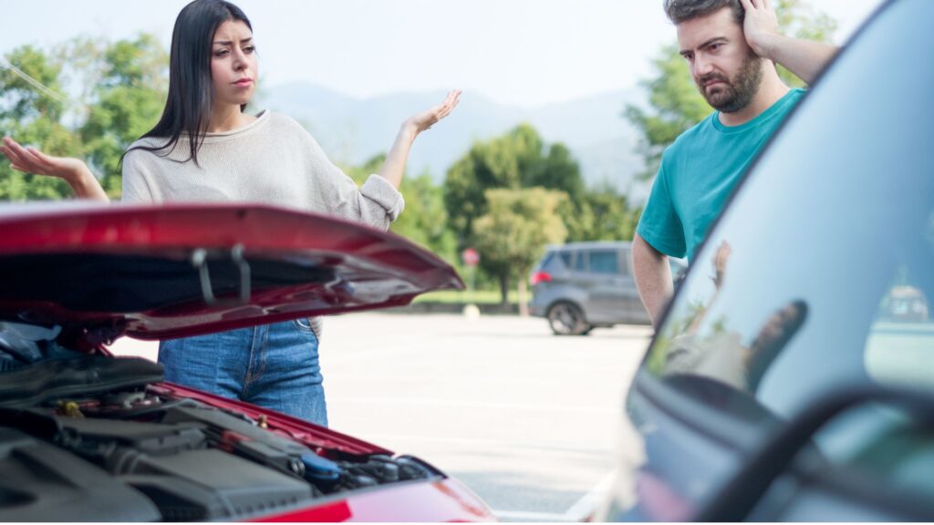 A man and a woman looking confused after getting involved in a car accident.