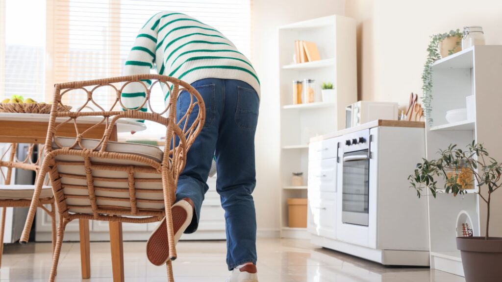 A person tripping from a chair in the kitchen.
