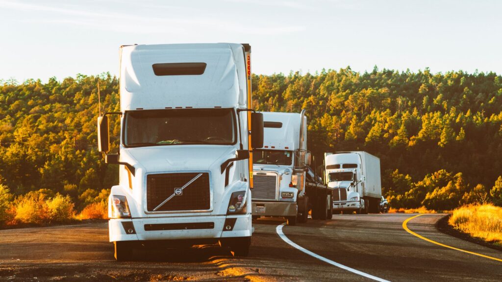 A row of large white trucks driving in a line.