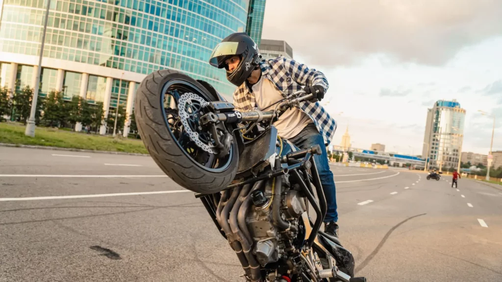 A man performing a wheelie on a street.