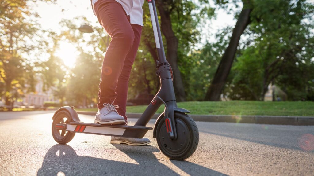 A person riding an electric scooter as the sun is setting in the background.