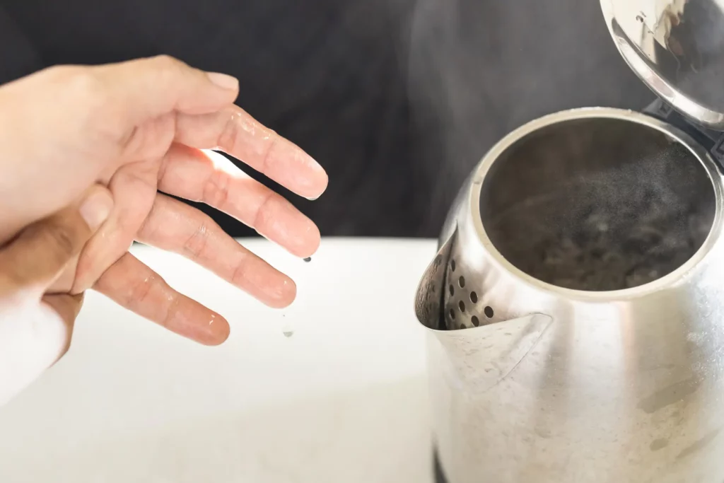 A person about to touch a hot kettle.