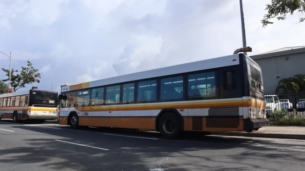 A city bus driving alongside a street.