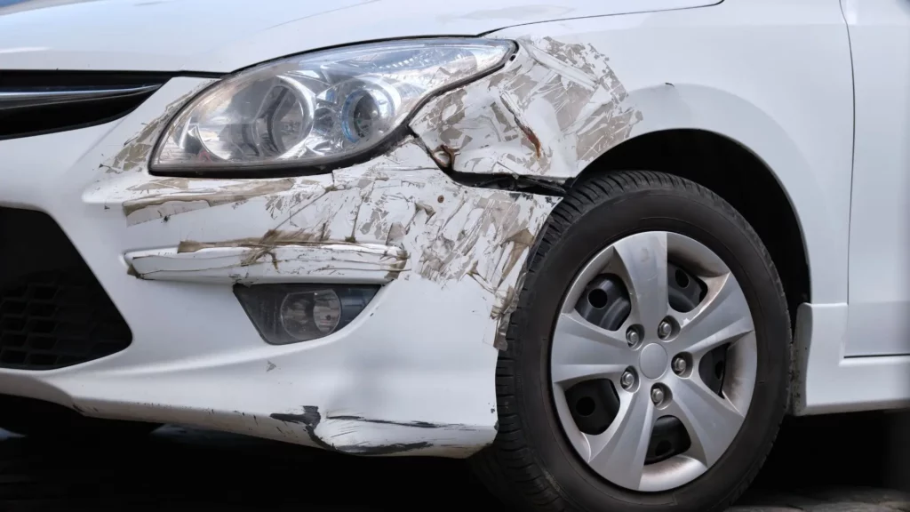 A huge scratch on a car's front bumper.