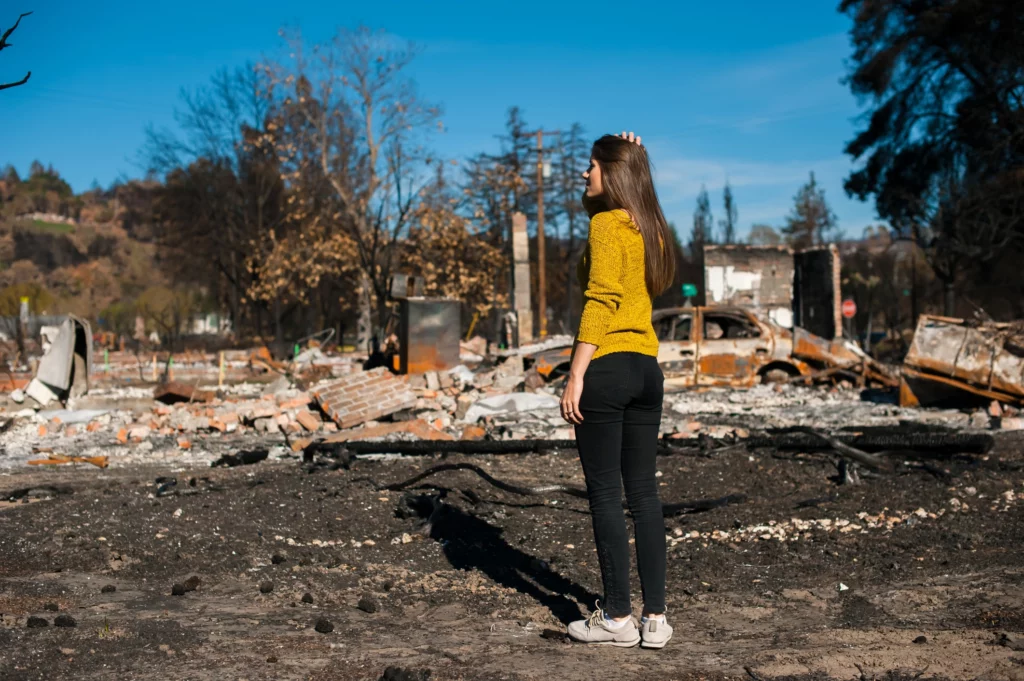 A woman looking at her burned down home.