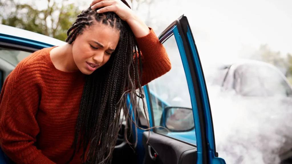 A woman who got into an accident and is holding her head as she gets out.