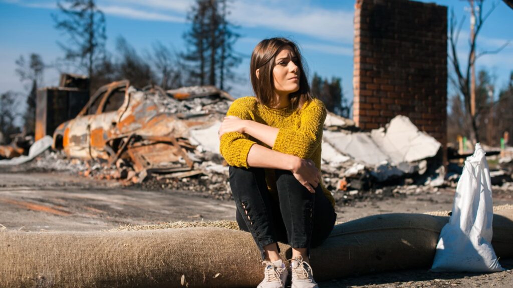 A woman sitting in front of her destroyed home.