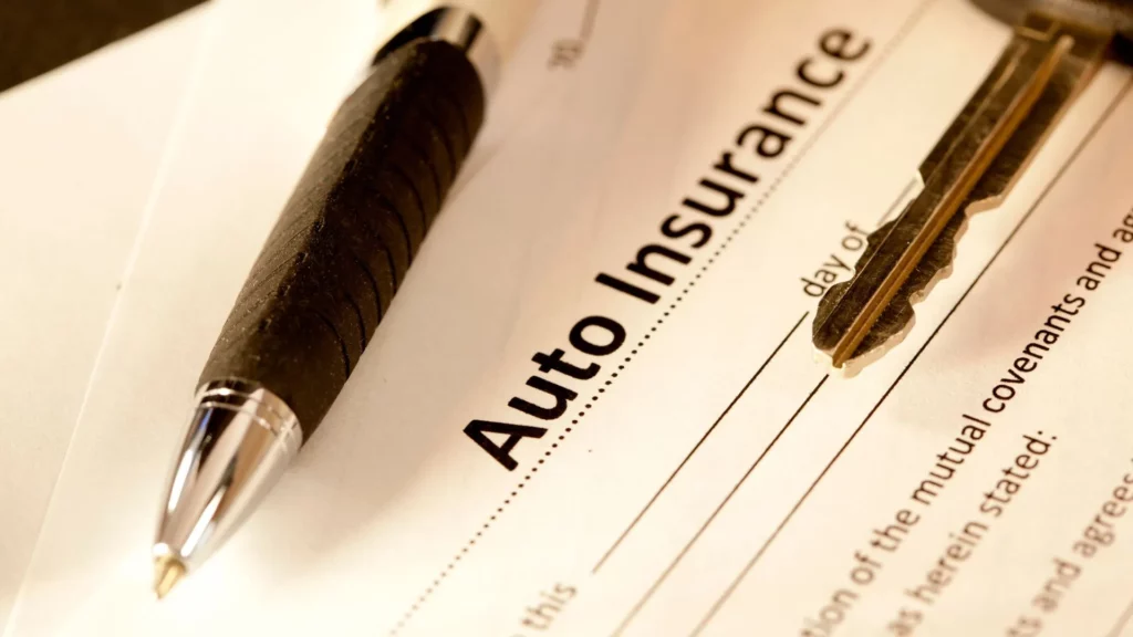 An auto insurance form with a pen and car key on the form.