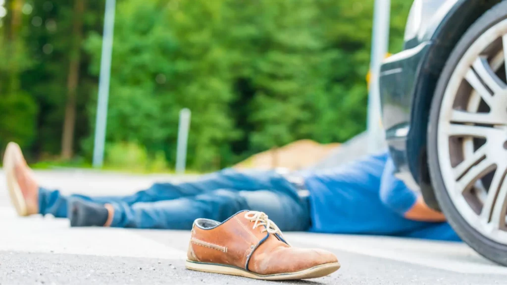 A man laying in the middle of the road, after getting into an accident.