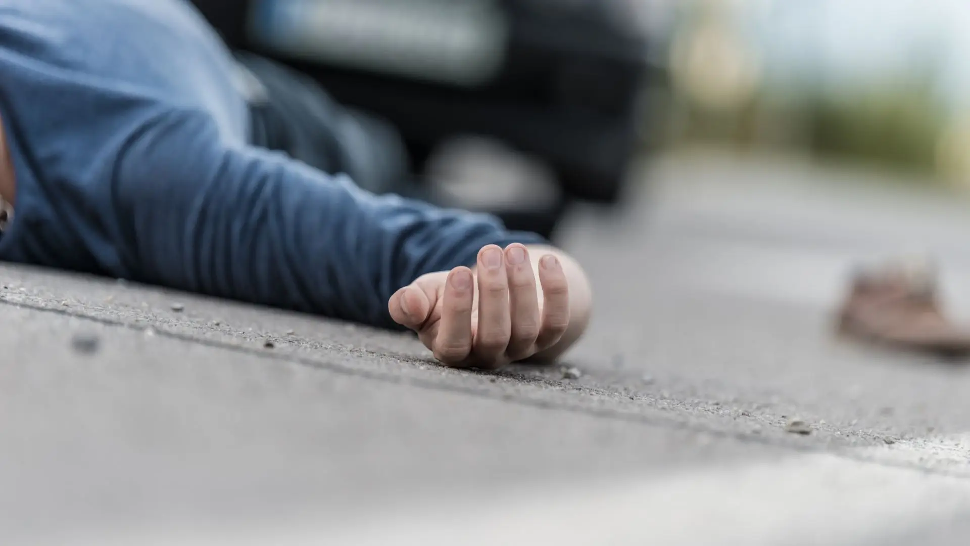 A man laying on the road, after getting hit by a car.