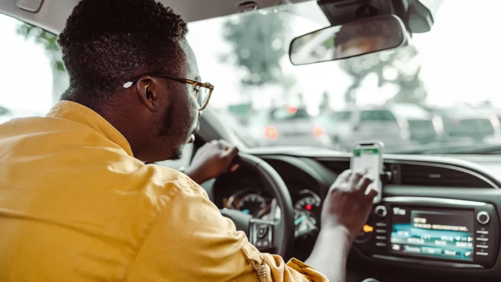An Uber driver who is managing incoming alerts on his phone.