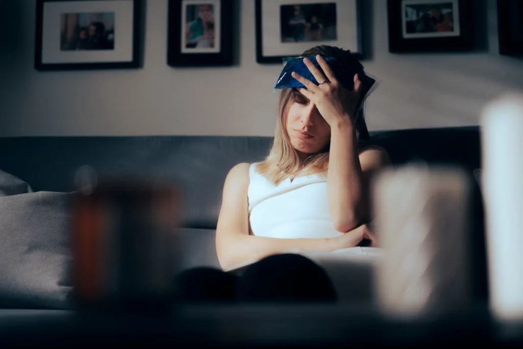 A woman putting an ice pack on her head.