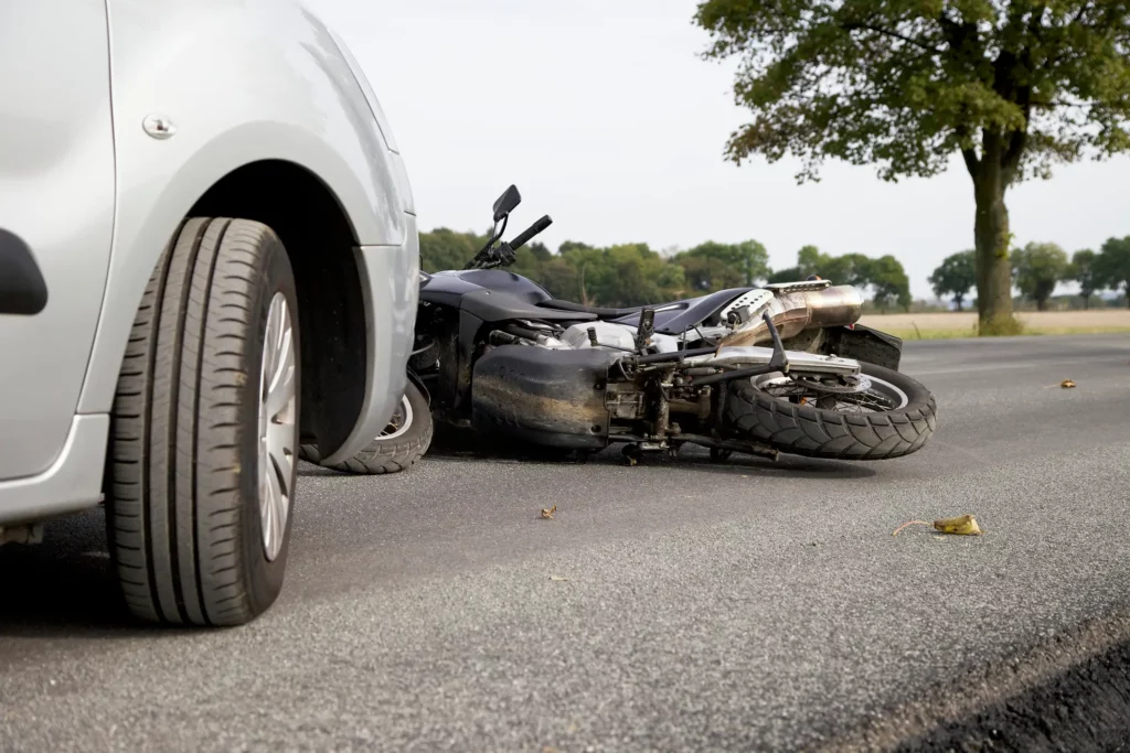 A motorcycle laying in front of a car, implying an accident had occurred.