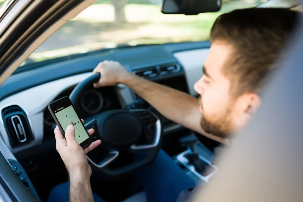 A man on his phone while driving his car.